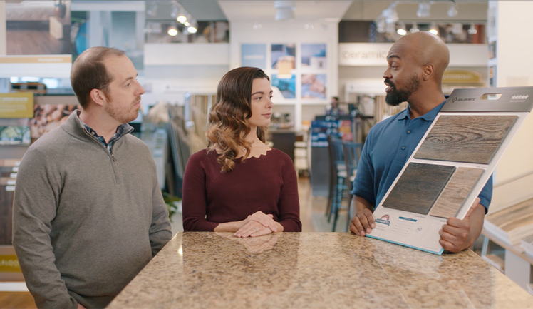 A couple looking at flooring samples with a sales person.